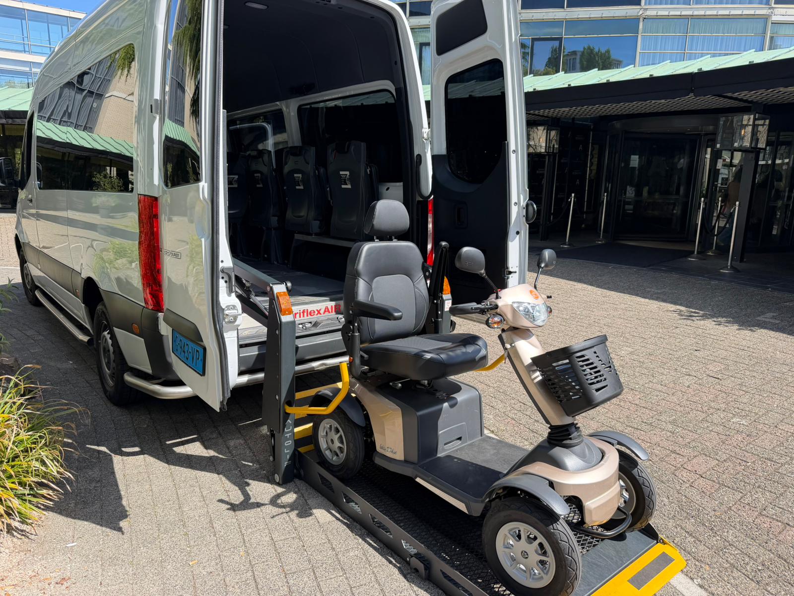 Scootmobiel op de elektrische laadklep van de rolstoelbus